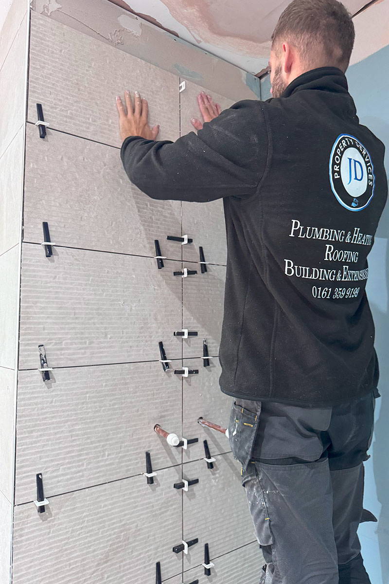 Worker tiling a bathroom wall